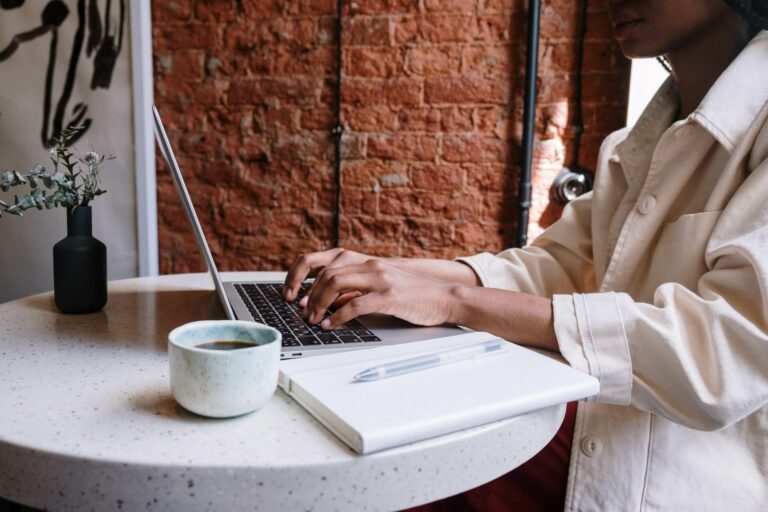 kvinna arbetar framför dator med en kopp kaffe