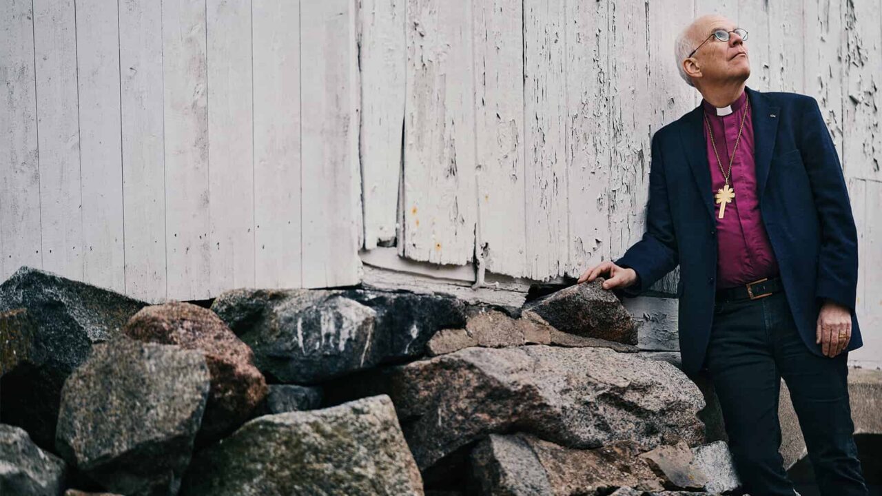 Porträttbild på ärkebiskop Martin Modéus som står vid ett par stenar