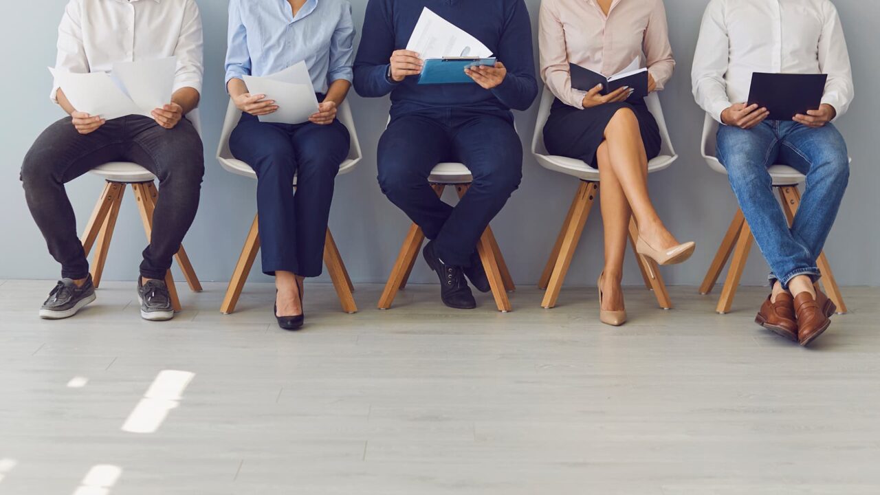 Bild på  människors nedre kroppar när de sitter på stolar i rad