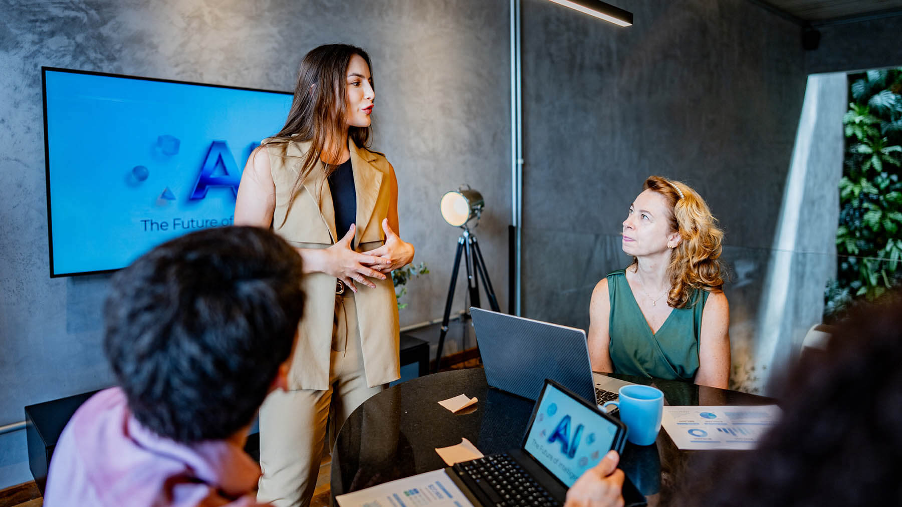 En kvinna håller en presentation för kollegor i ett modernt mötesrum.