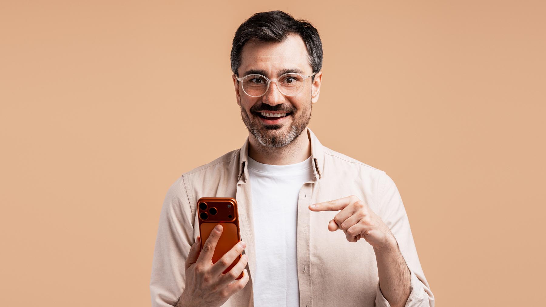 En glad man pekar mot sin mobiltelefon.