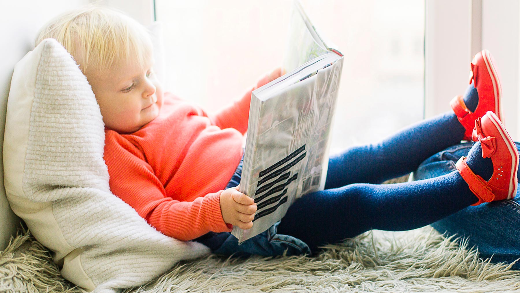 Ett barn i röd tröja som läser en bok
