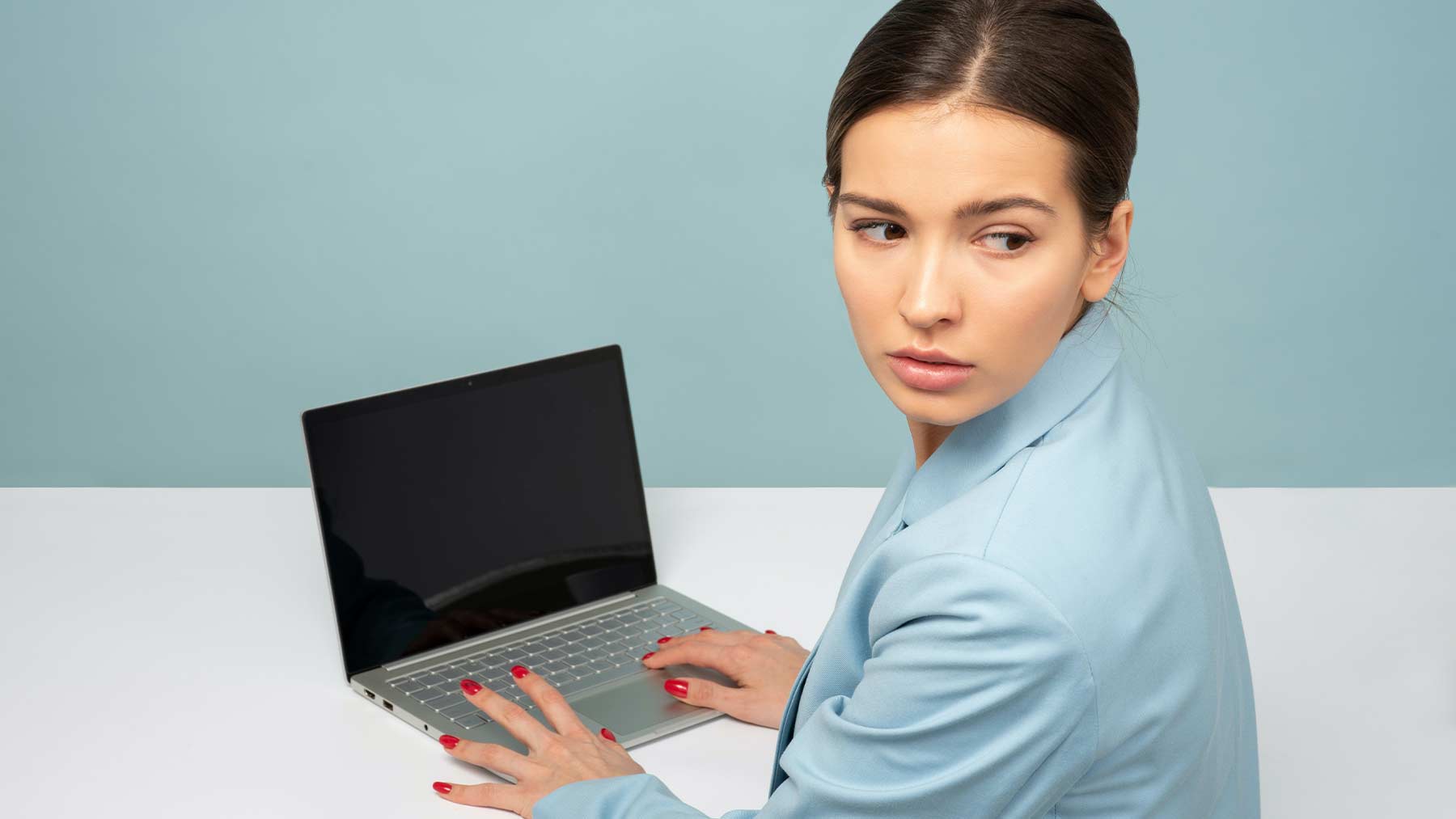En kvinna som sitter vid en dator tittar bakåt och ser orolig ut.