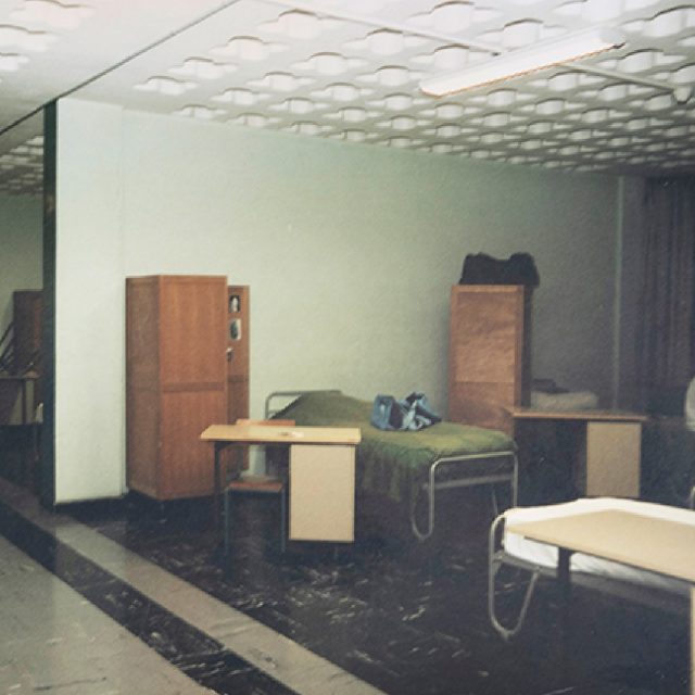 Interiör från internatskolan i Frankrike där Linda H Staaf bodde som tonåring. En stol, ett skrivbord och en säng i en sal som delades med många andra.