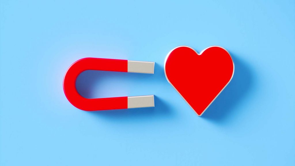 social-media-and-online-dating-concept-red-heart-shape-gravitated-towards-a-red-magnet-on-blue-background